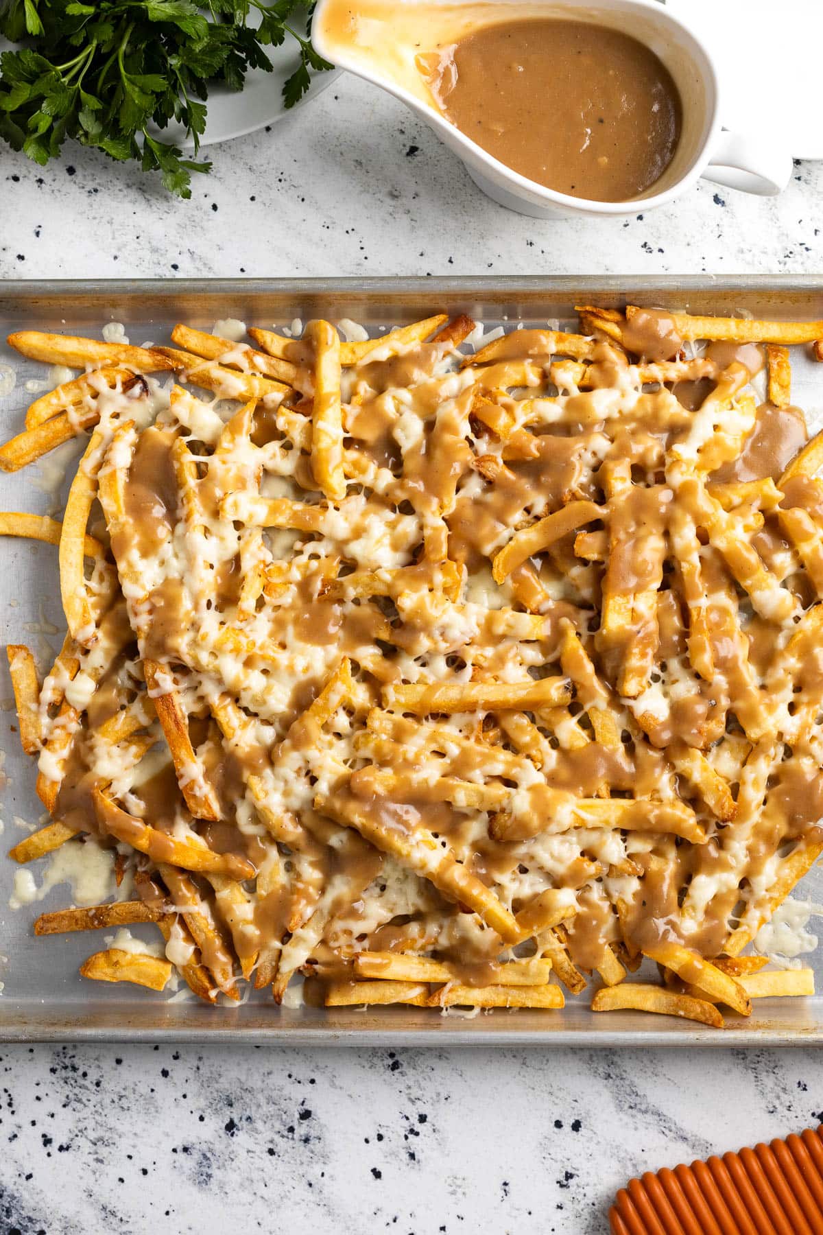 A batch of disco fries freshly prepared on a large sheet pan.