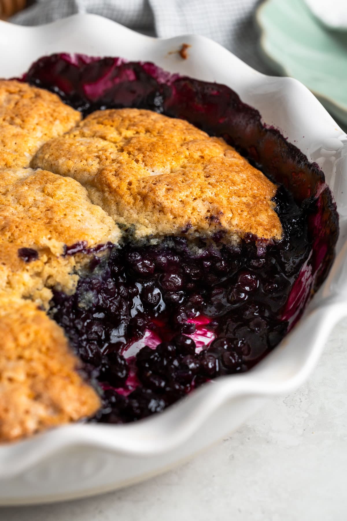 A serving removed from a pan of blueberry cobbler.