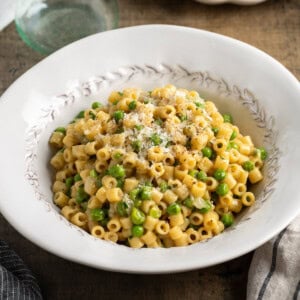 A serving bowl of pasta and peas sprinkled with Pecorino.