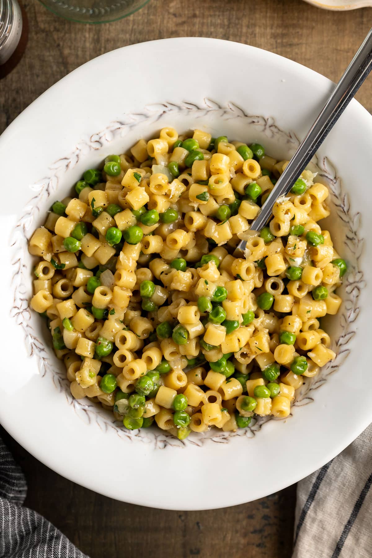 A spoon in a bowl of ditalini pasta with peas.