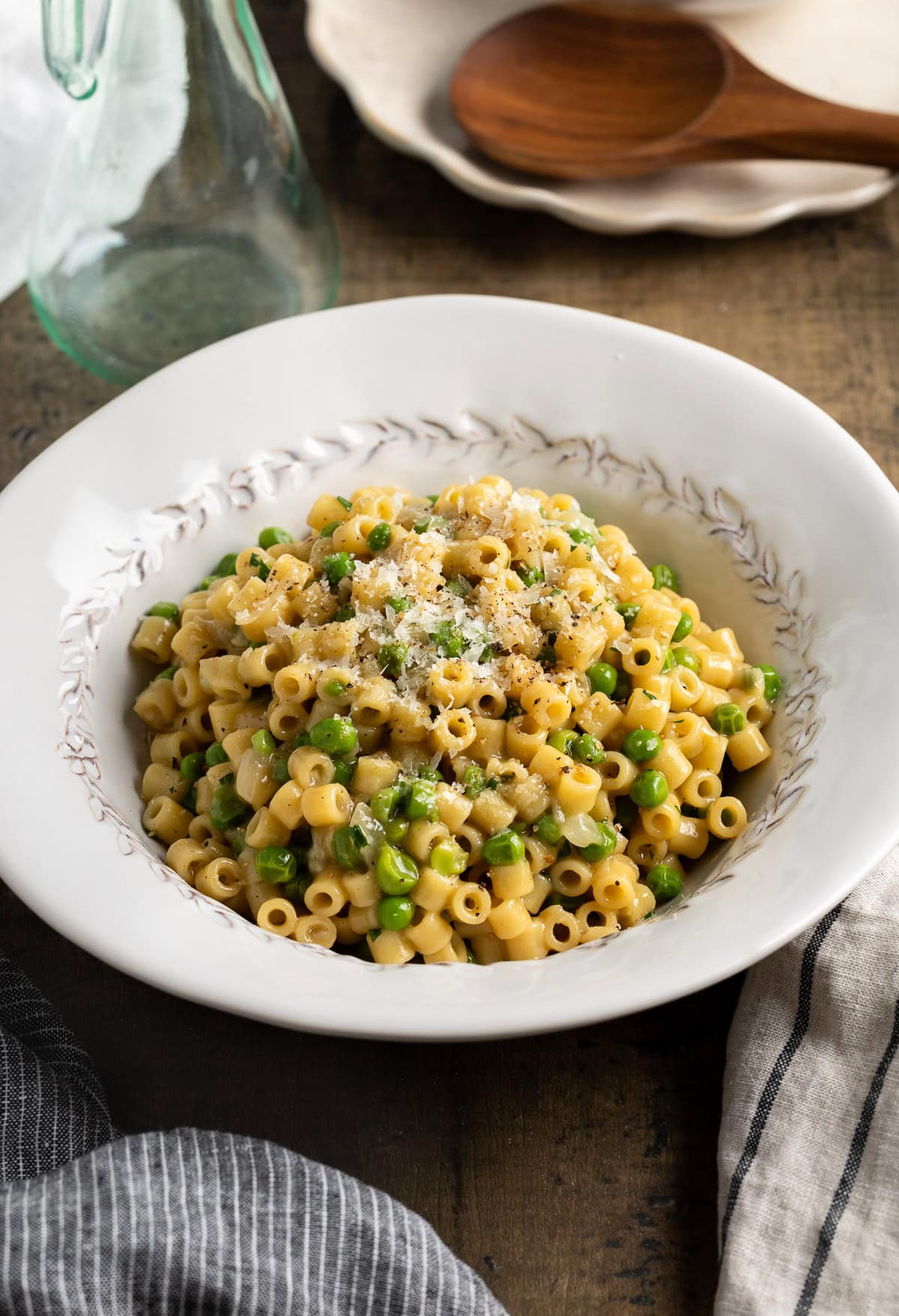 A serving bowl of pasta and peas sprinkled with Pecorino.