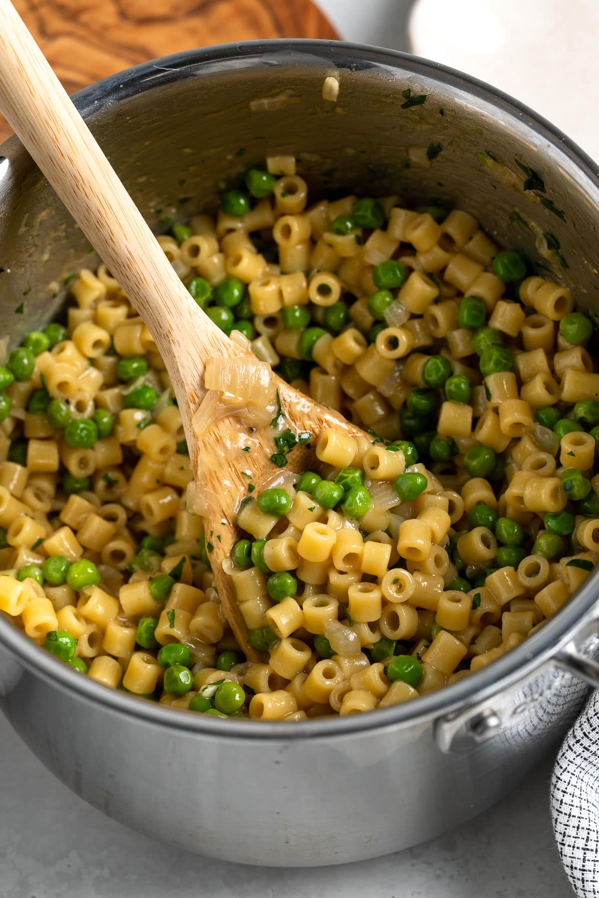 Al dente ditalini and peas in a pot with a wooden spoon ready to serve.