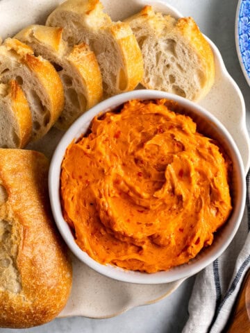 Hot honey butter in a bowl next to a sliced loaf of bread.