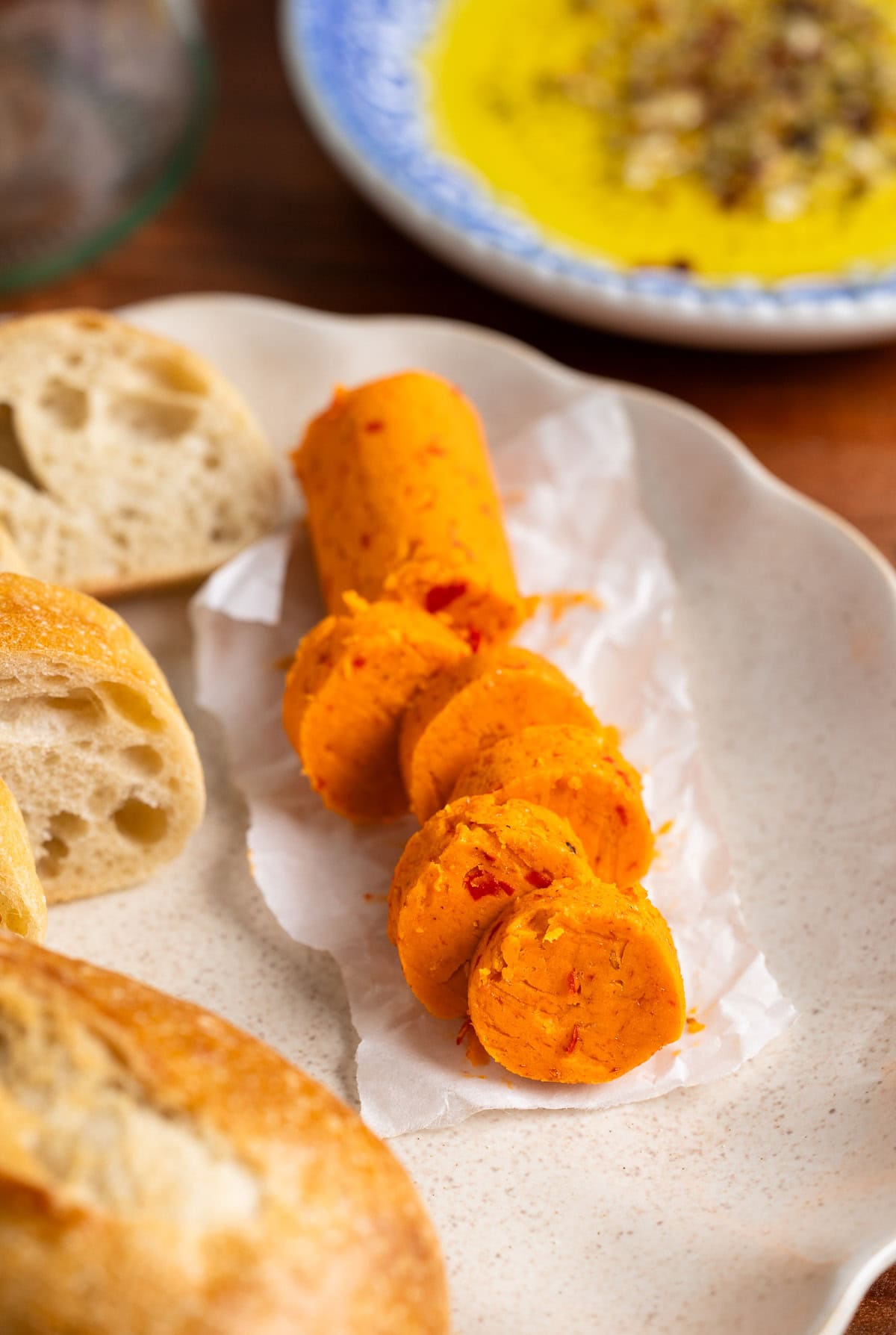 A log of Calabrian chili butter sliced on a plate with bread.