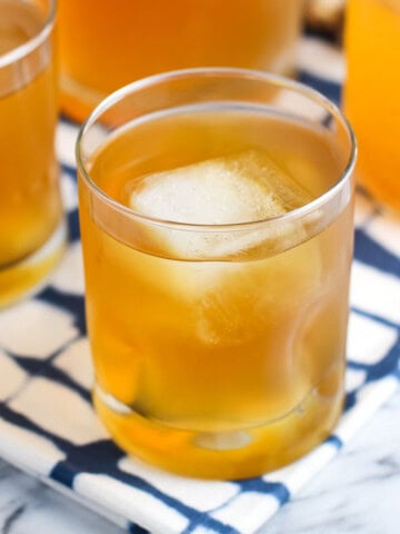 A glass of lemon ginger iced tea with a big ice cube.