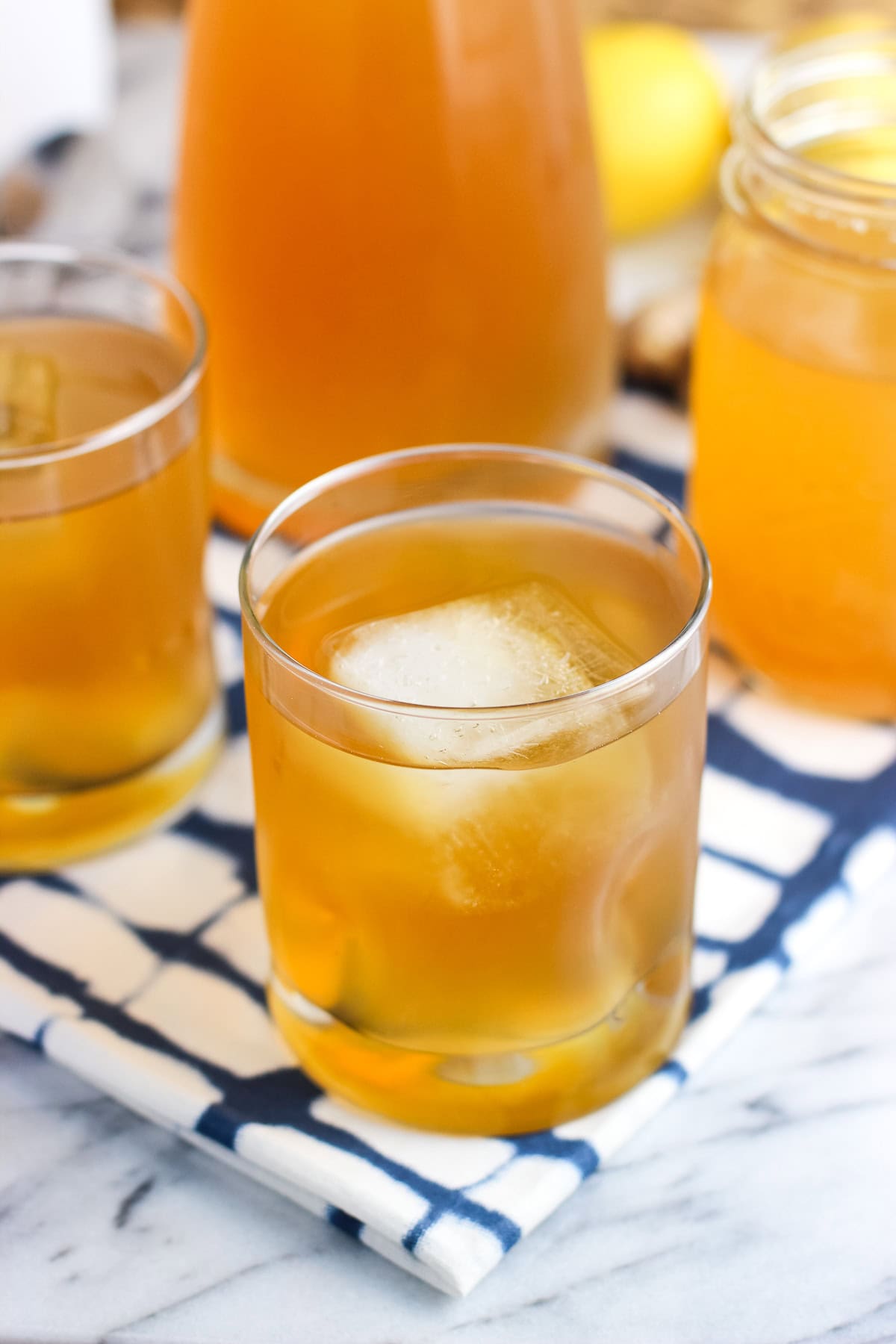 A glass of lemon ginger iced tea with a big ice cube.
