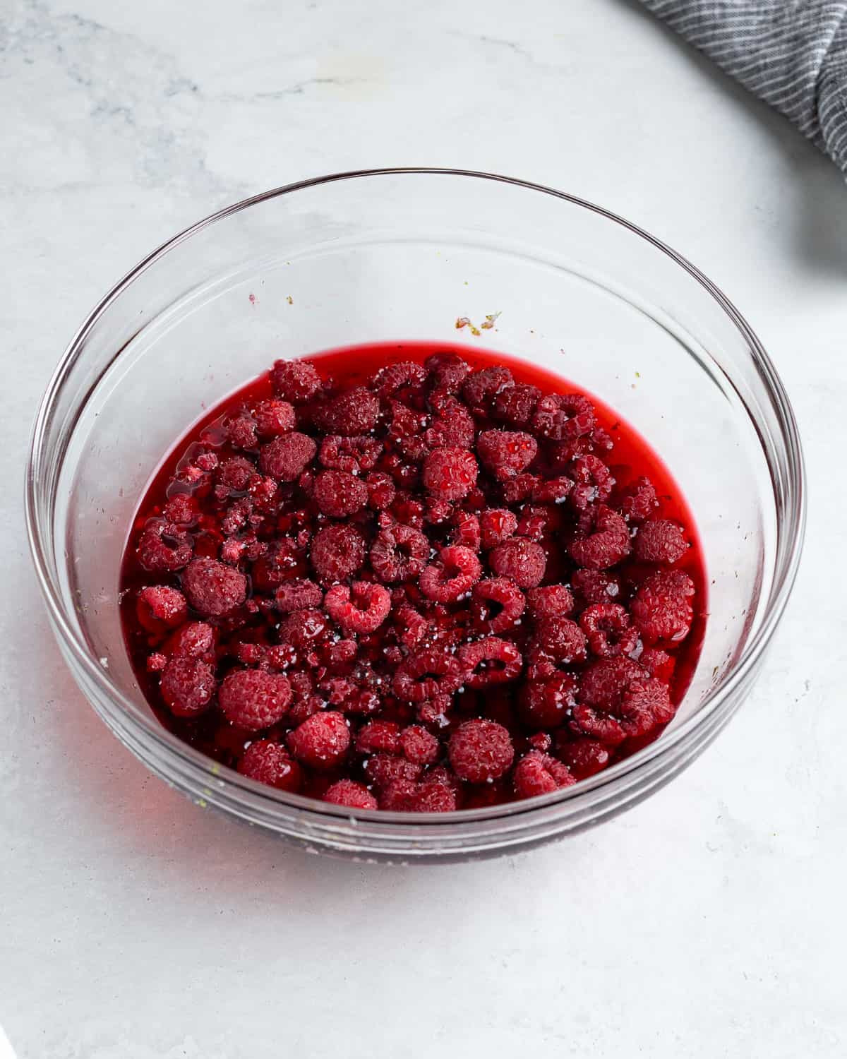 Raspberries, sugar, and lime zest in a bowl after steeping.