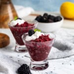 Cups of blackberry granita served with a dollop of whipped cream, whole blackberries, and mint.