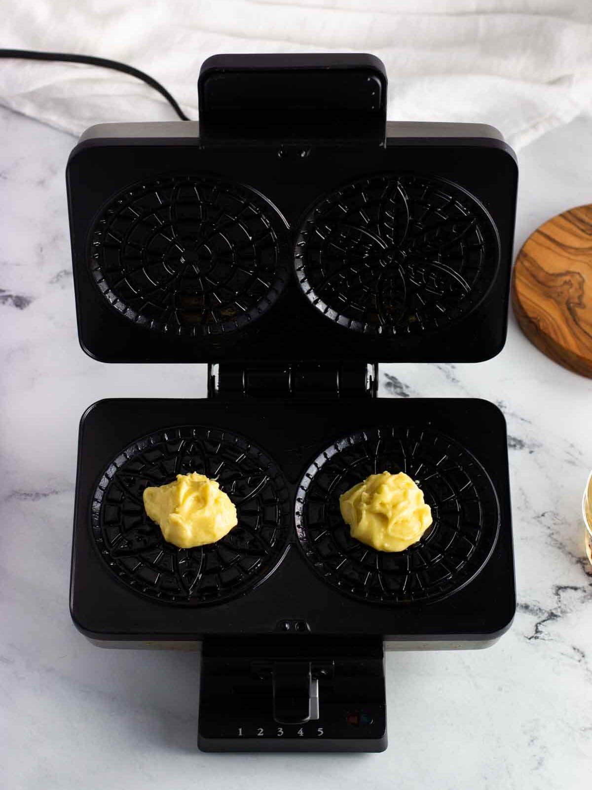 Two ball of batter on the open pizzelle press.
