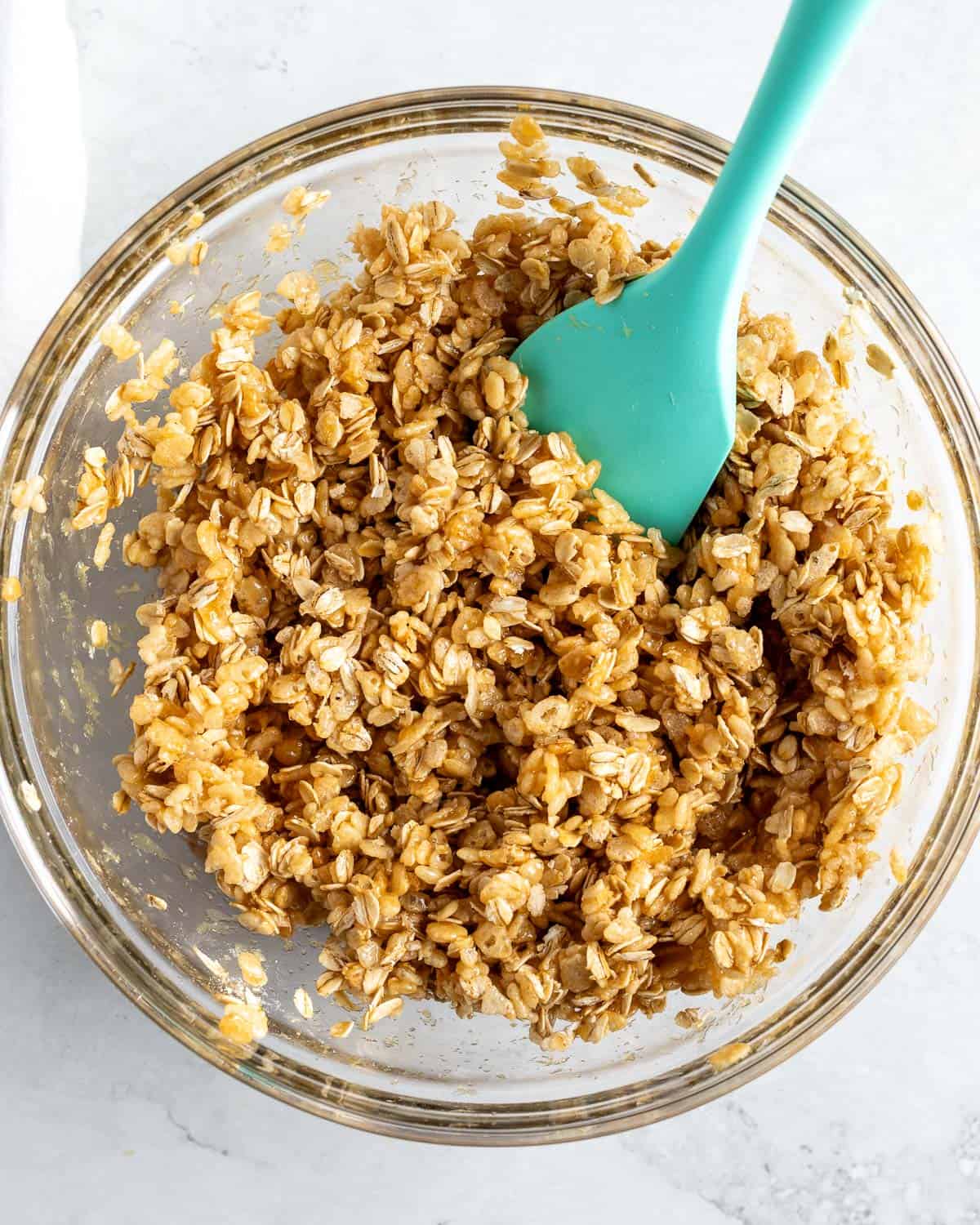 The liquid ingredients poured into the bowl of oats and cereal.