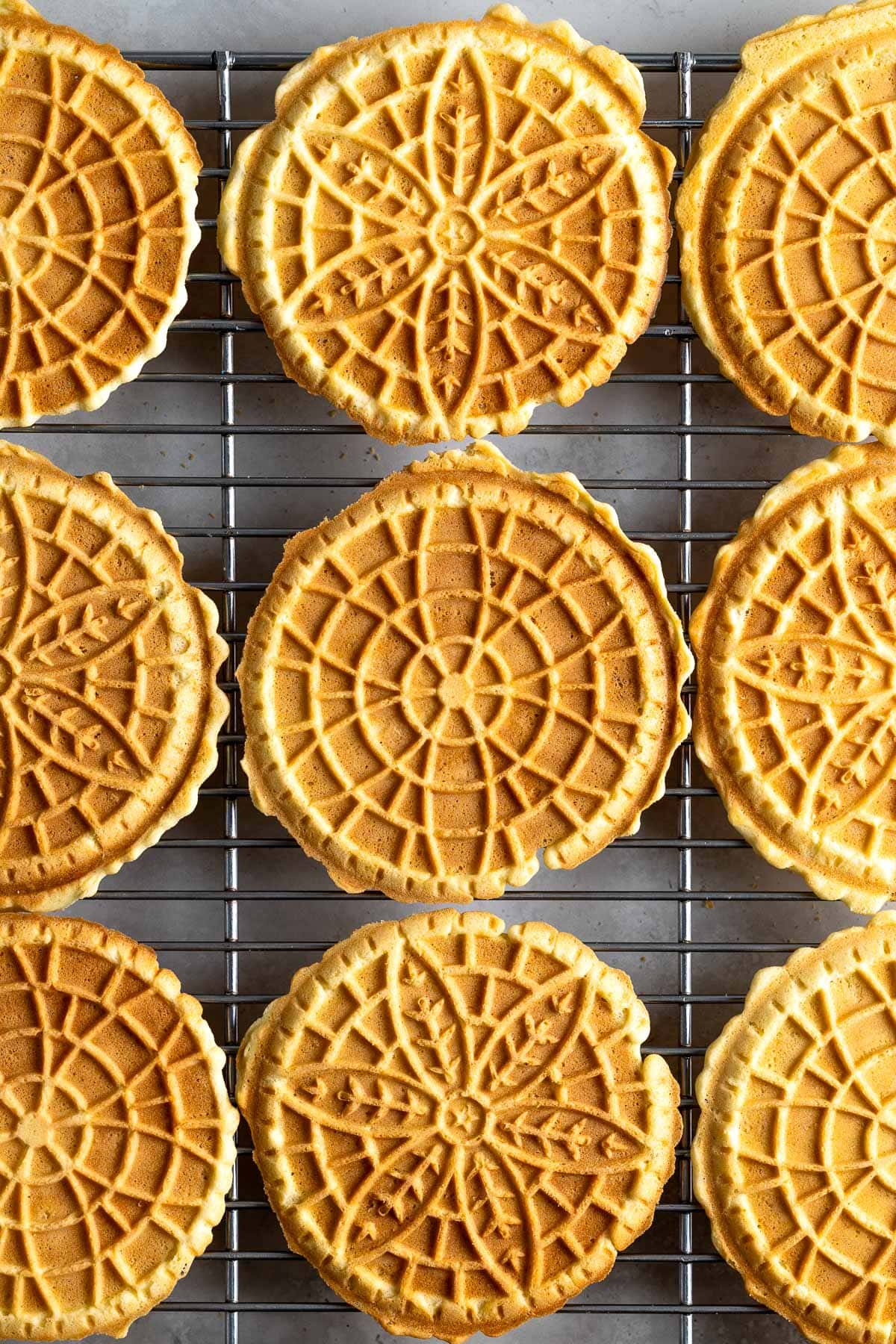 Cooked pizzelle on a wire rack.