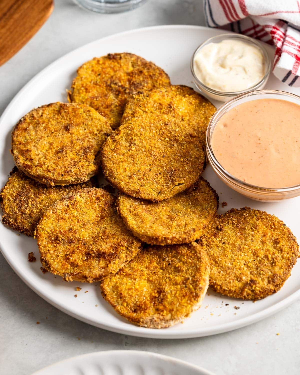 A plate of fried green tomato slices served with two dipping sauces.