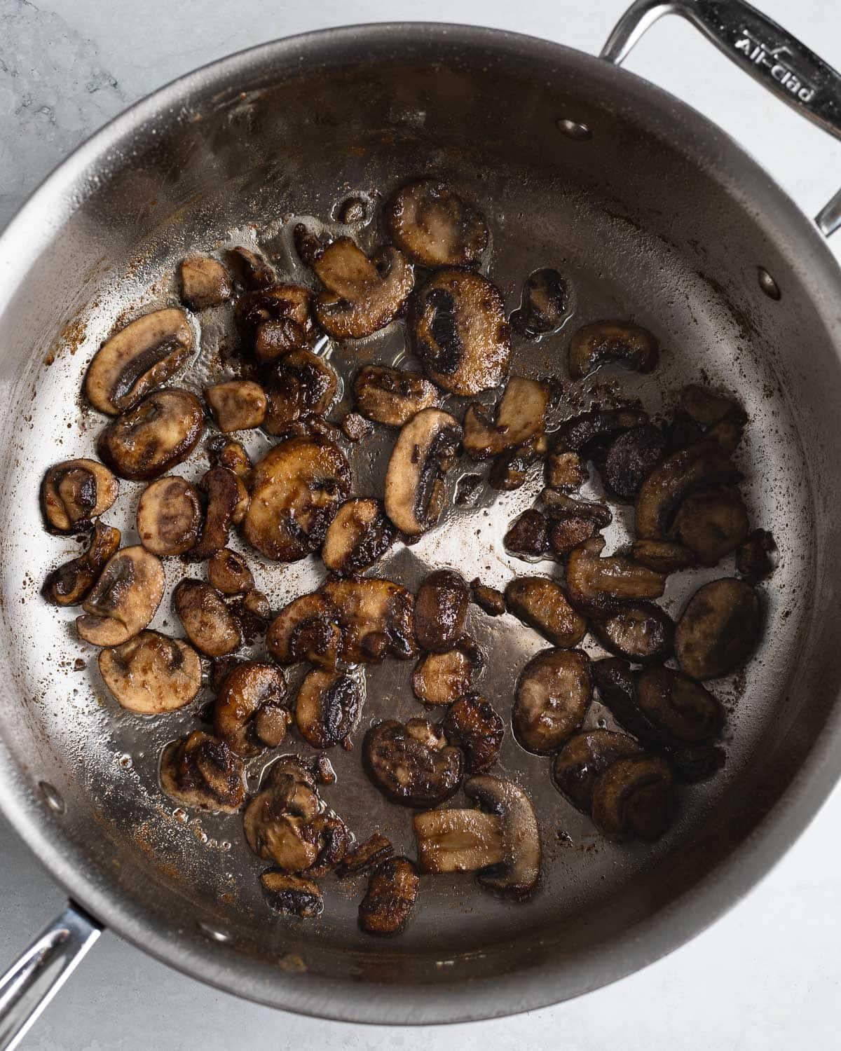 Mushrooms sautéing in a pan.