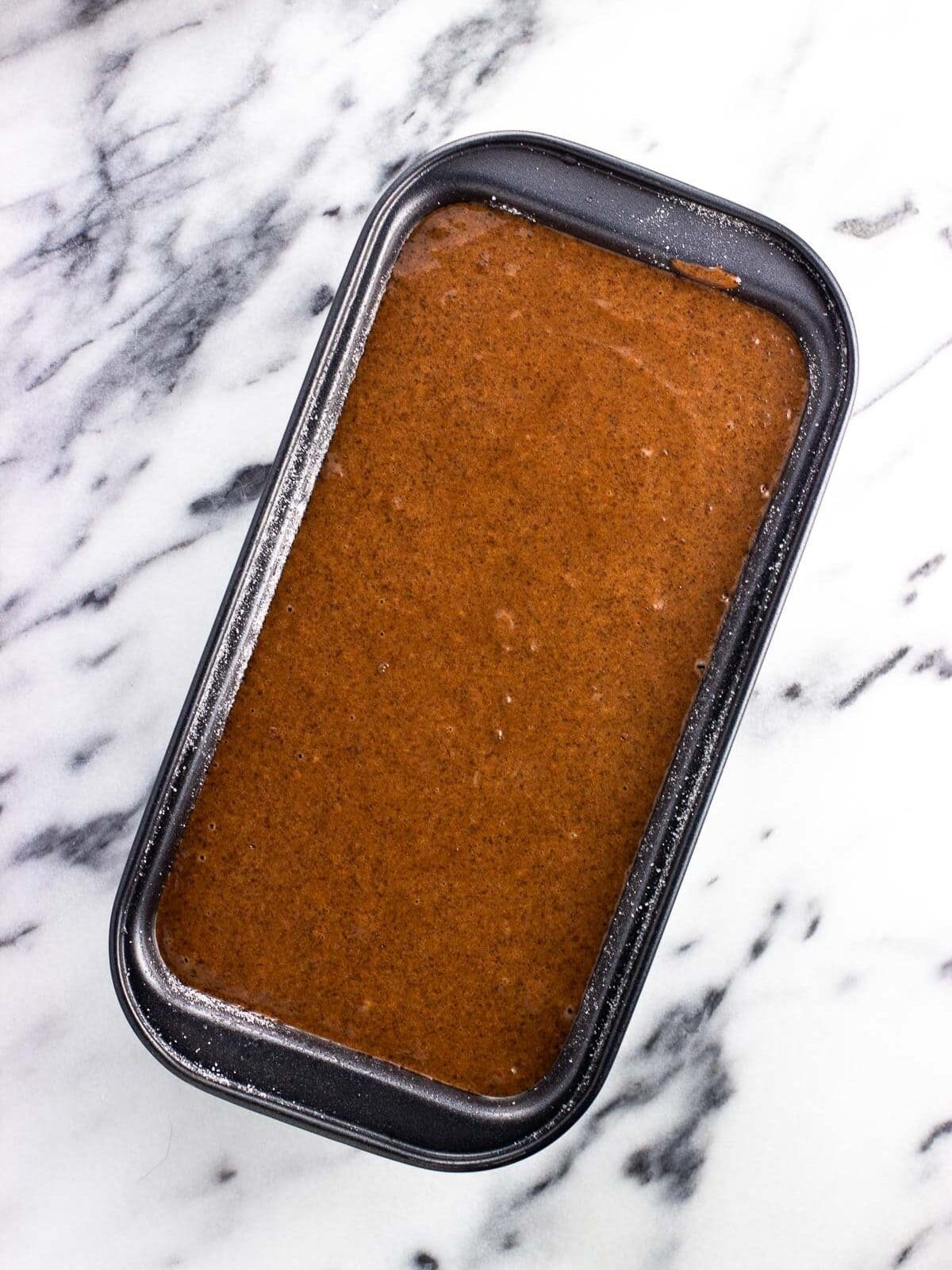 Chocolate cake batter poured into a sugared loaf pan.