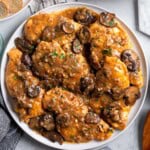A platter of chicken marsala covered in mushrooms and sauce.