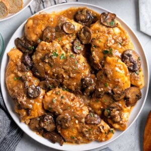 A platter of chicken marsala covered in mushrooms and sauce.