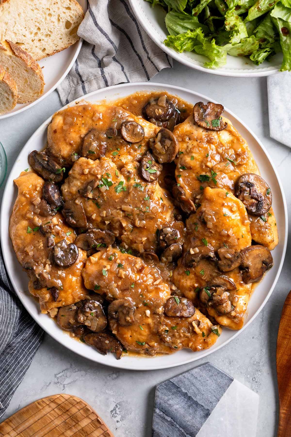 A platter of chicken marsala covered in mushrooms and sauce.