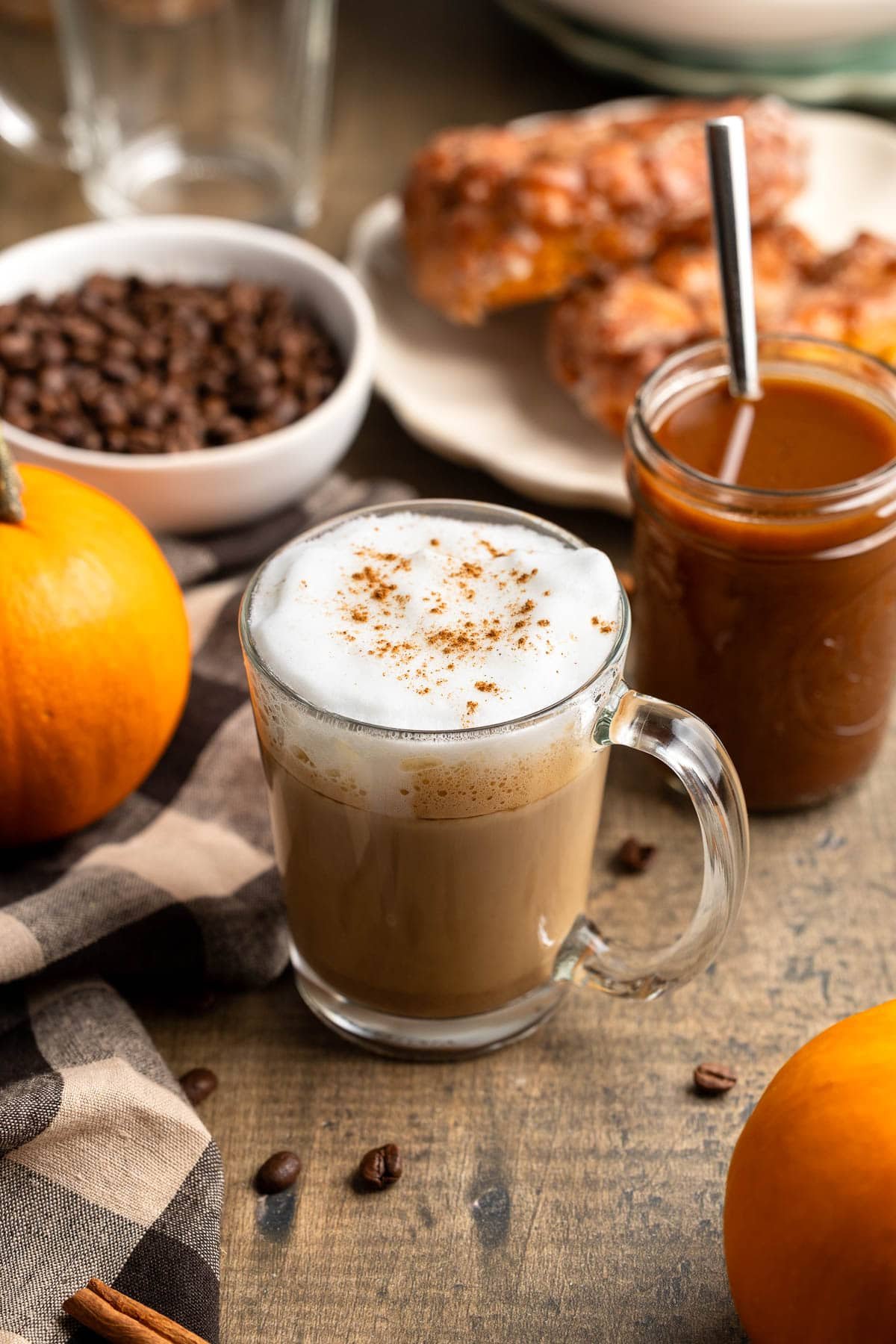 A maple pumpkin spice latte in a clear mug dusted with cinnamon.