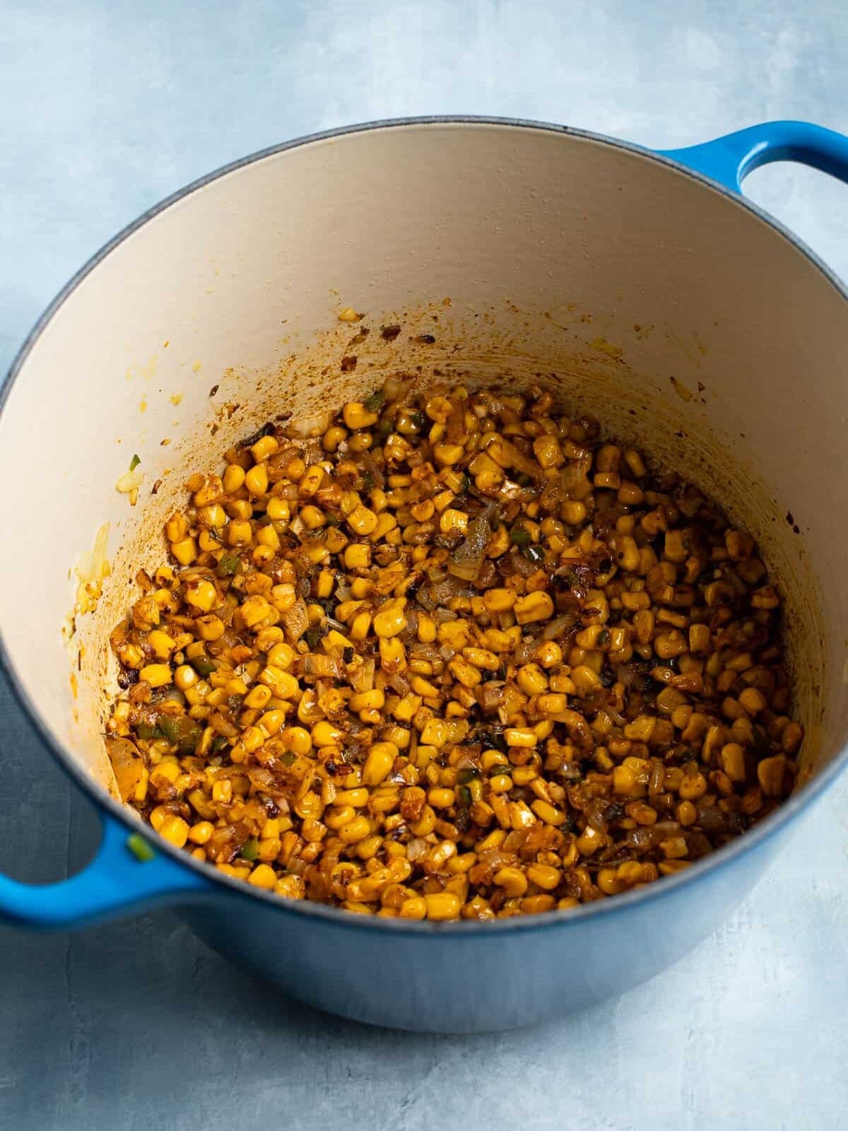 Seasoned roasted corn and vegetables in a large pot.