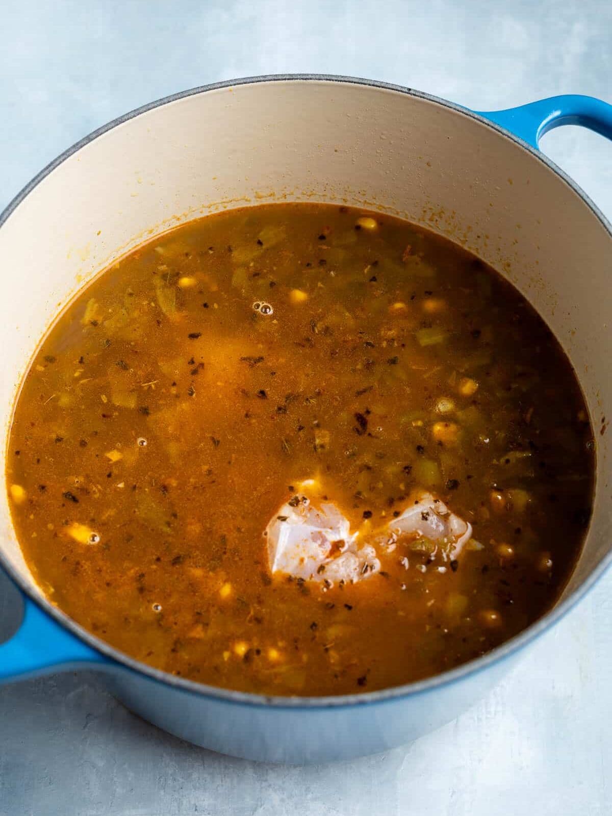 Broth and chicken added to the pot before simmering.