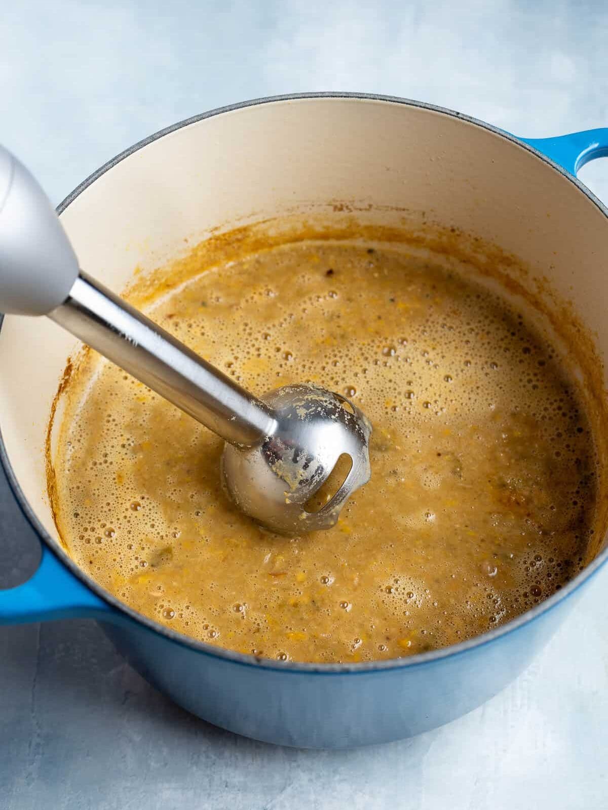 An immersion blender pureeing the chili.