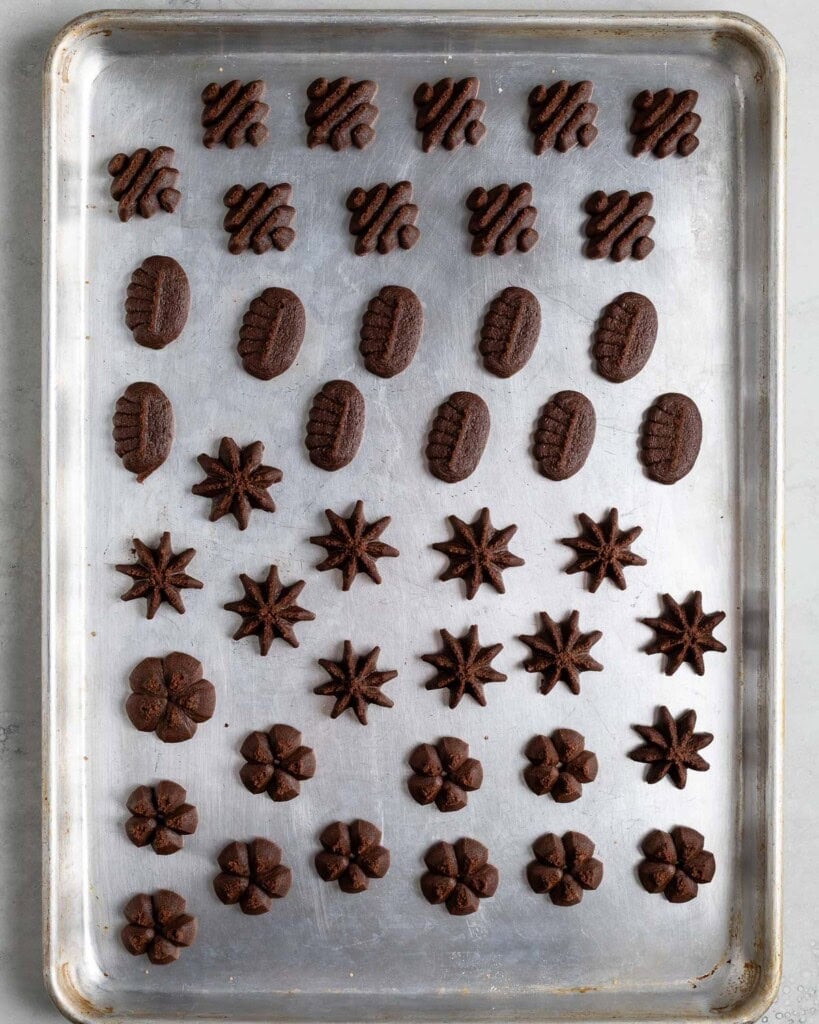 A variety of pressed cookies on a large sheet pan before baking.