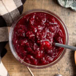 Slightly spicy cranberry sauce in a glass bowl with a spoon in it.