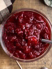 Slightly spicy cranberry sauce in a glass bowl with a spoon in it.
