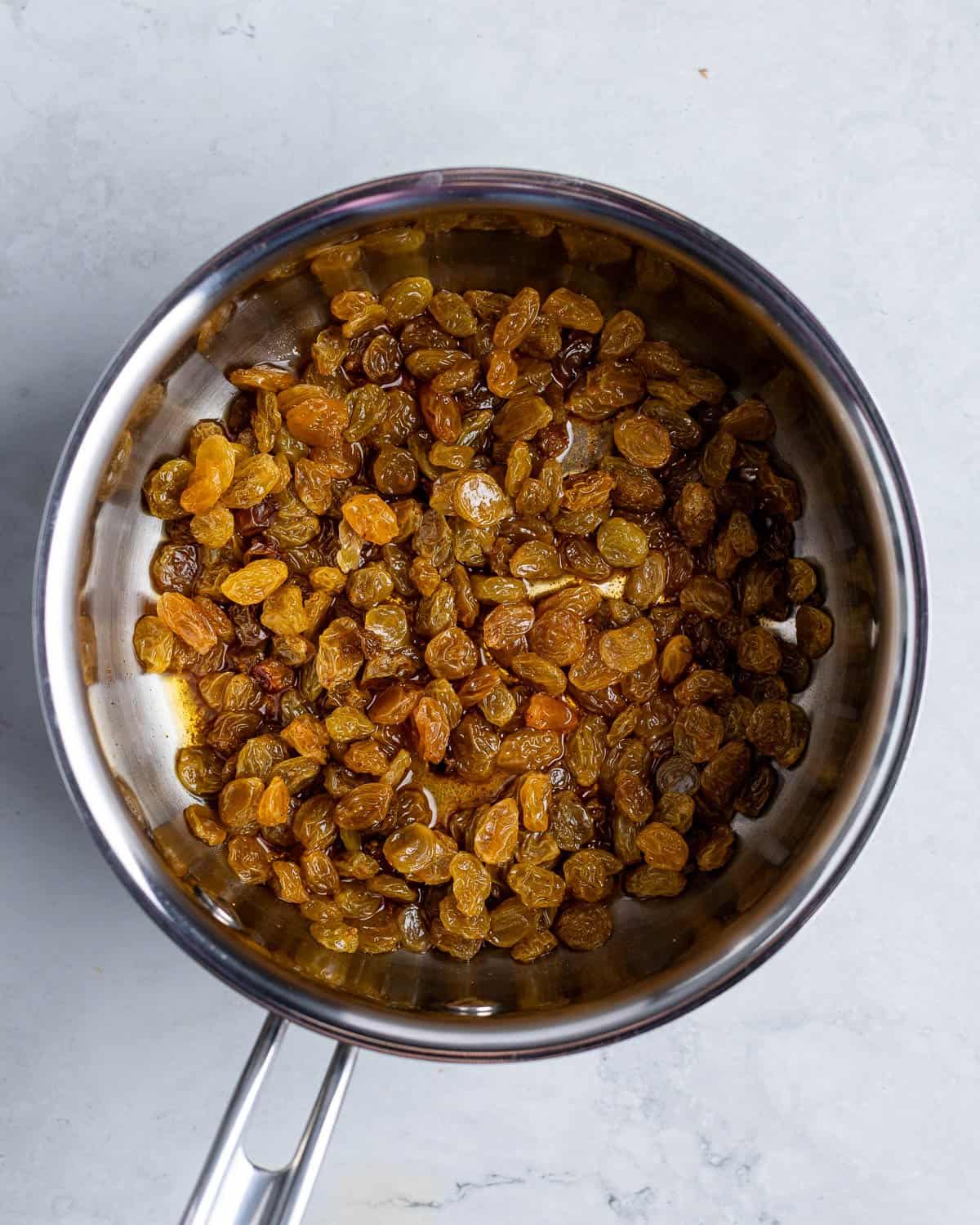 Raisins soaking in bourbon and cinnamon in a pan.