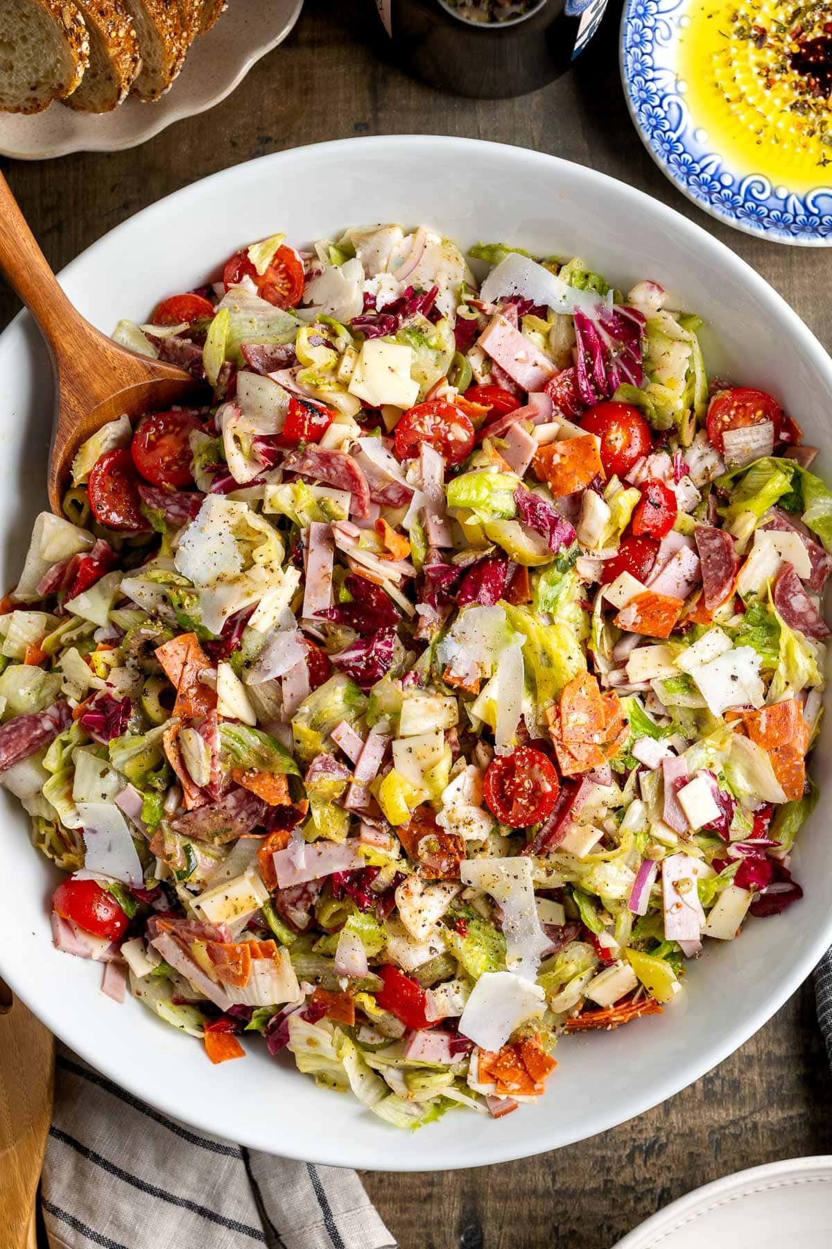 Chopped Italian sub salad in a large serving bowl with a wooden spoon.
