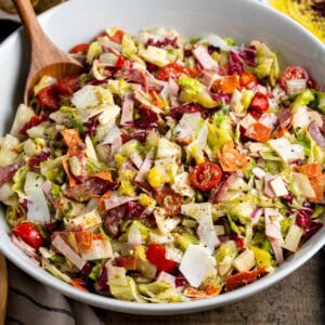 A large Italian sub salad in a serving bowl with serving spoon.