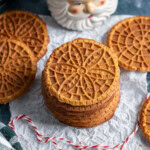 A stack of gingerbread pizzelle next to a santa mug.