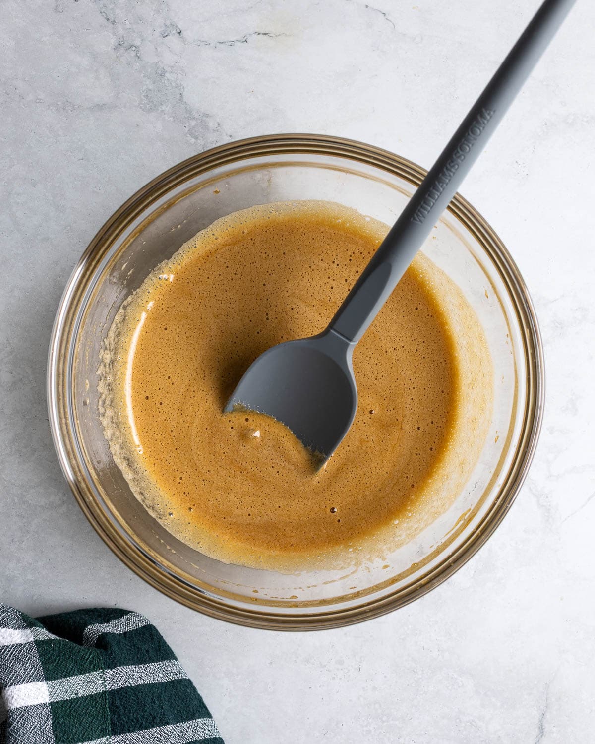 Oil and sugar mixed together in a bowl with a spatula in it.