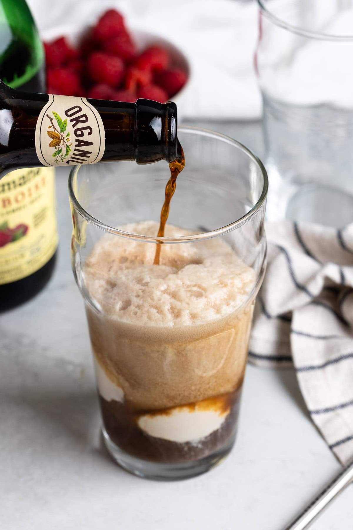 Chocolate stout foaming up being poured into a glass over vanilla ice cream.