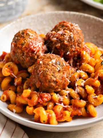 Fiber-rich turkey meatballs served on a plate of pasta and marinara sauce.