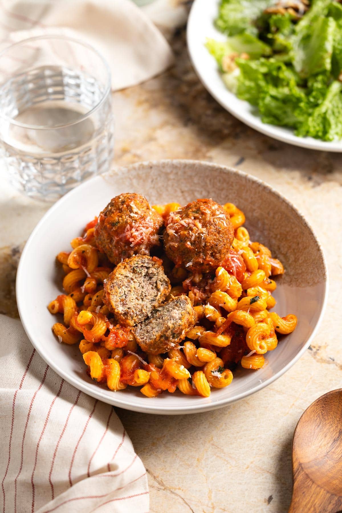 Meatballs and pasta with one meatballs cut open.