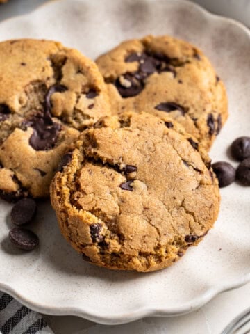 Three golden-brown chocolate chip cookies made with olive oil.