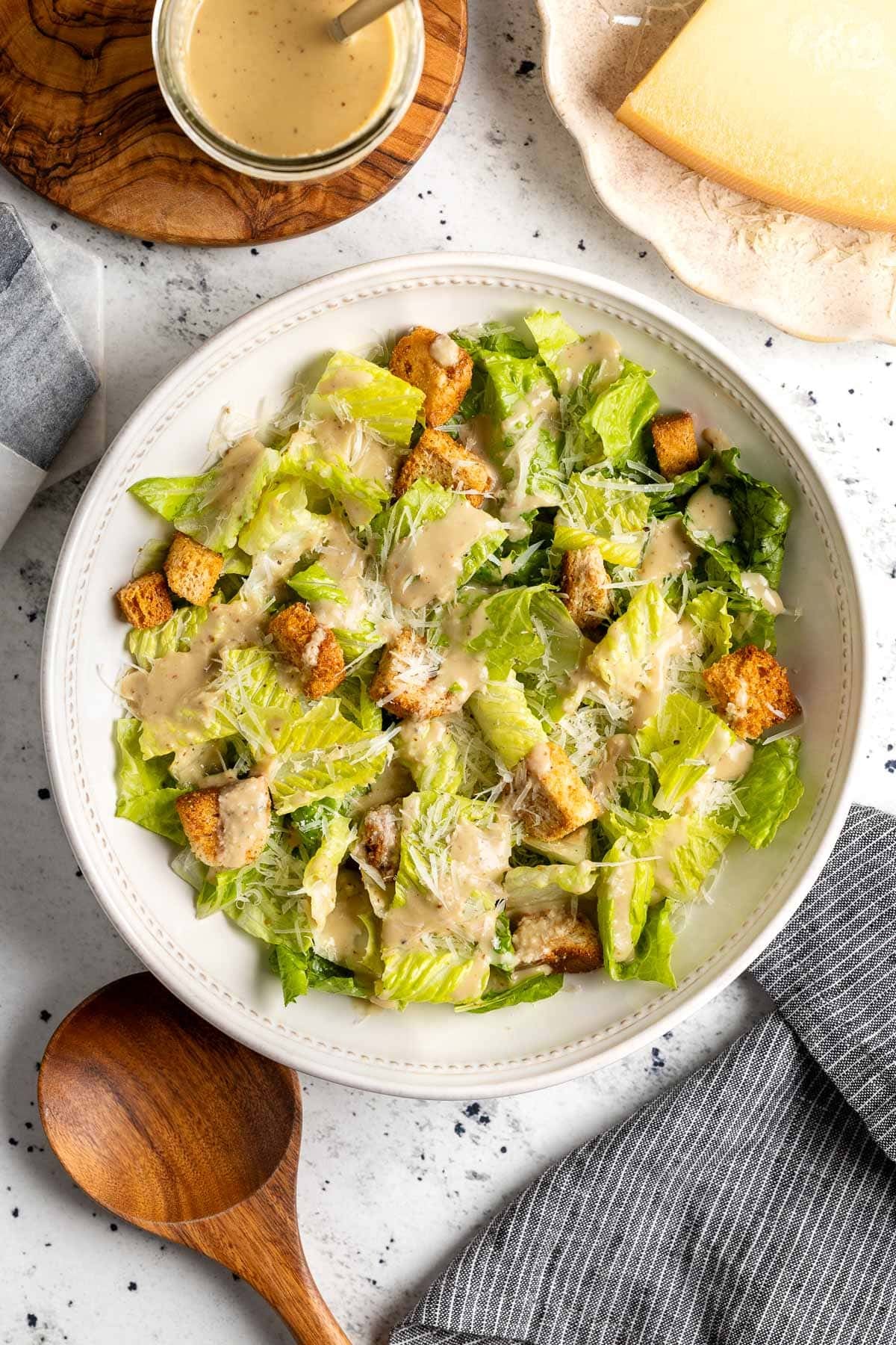 Creamy caesar vinaigrette dressing a salad with grated Parmesan and croutons.