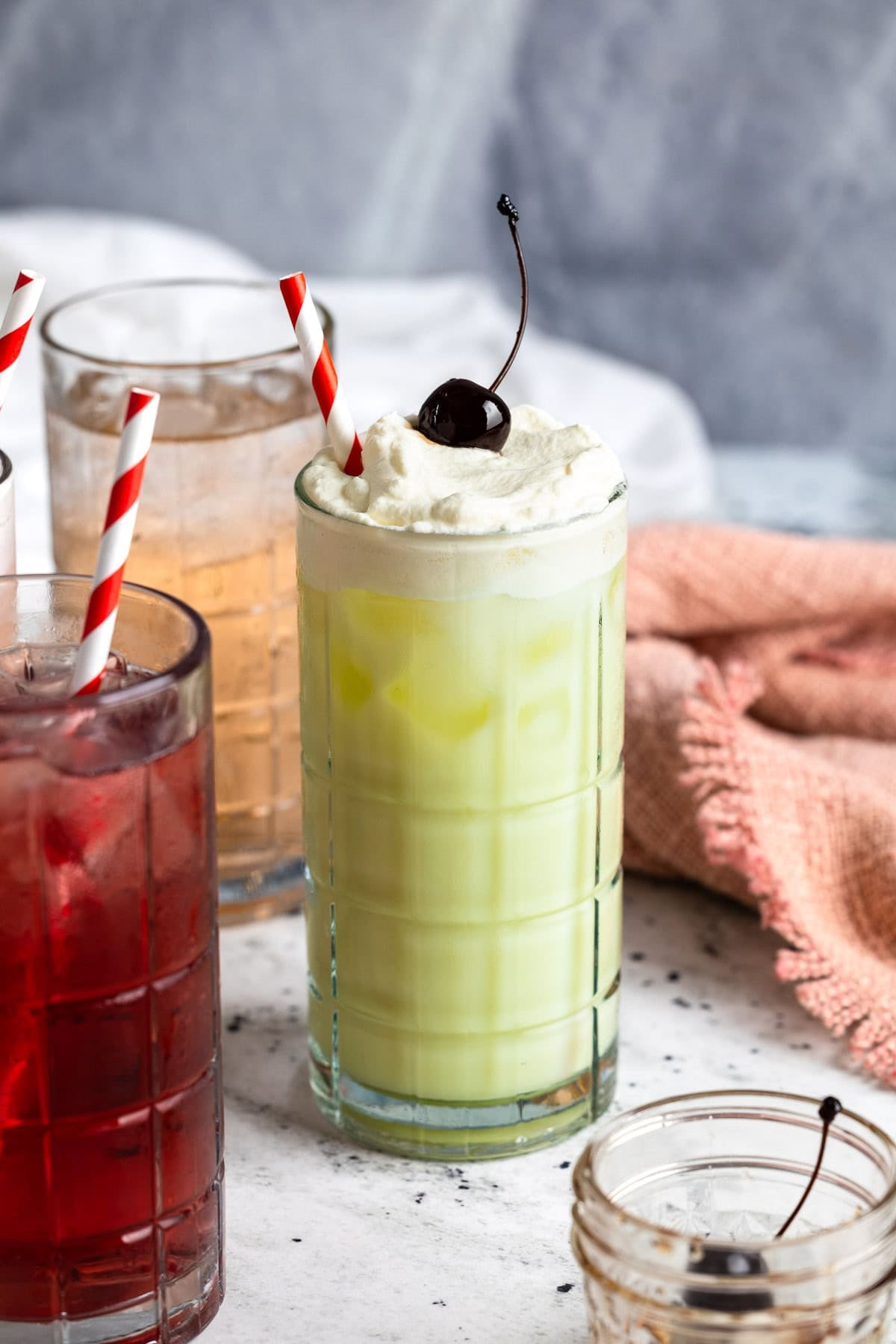 An Italian pistachio cream soda topped with whipped cream and a cherry.