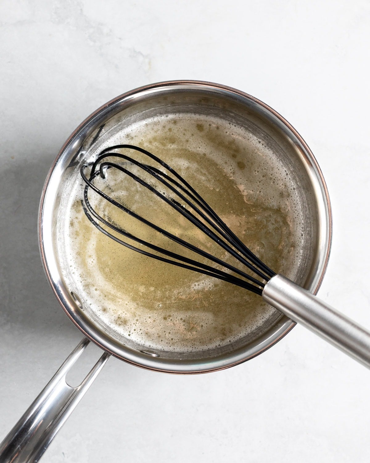 Gelatin, juice, sugar, and corn syrup heated and whisked together in a pan.