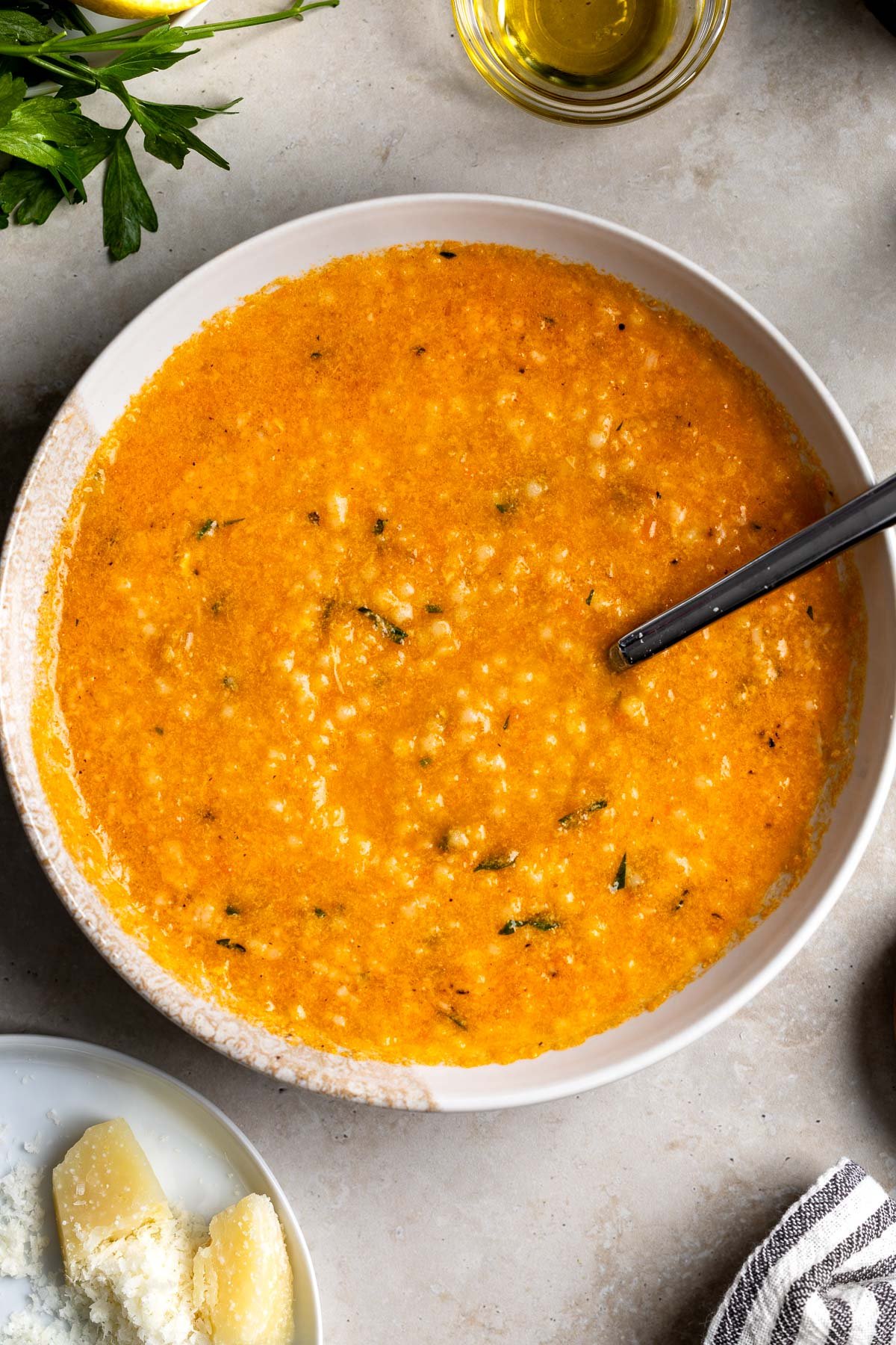 A bowl of pastina soup with egg with a spoon in it.