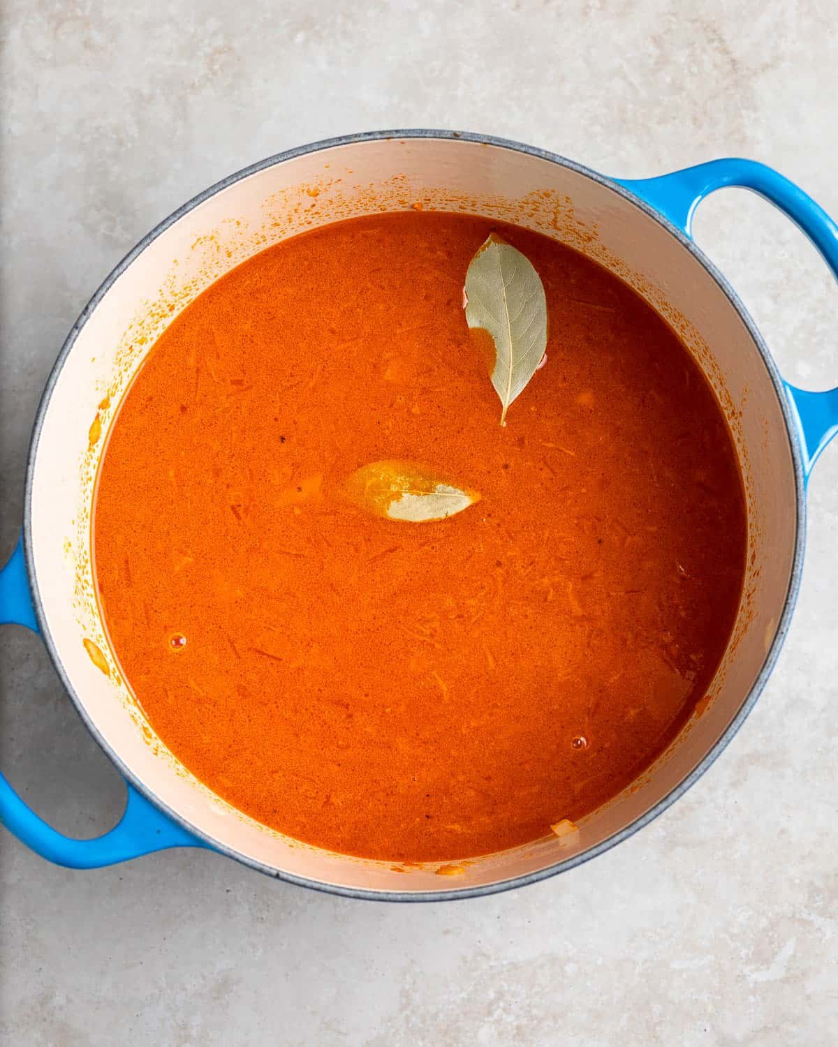 Broth and bay leaves added to the pot before simmering.