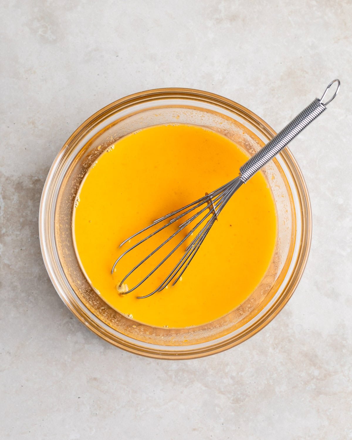 Eggs whisked together with hot broth in a bowl.