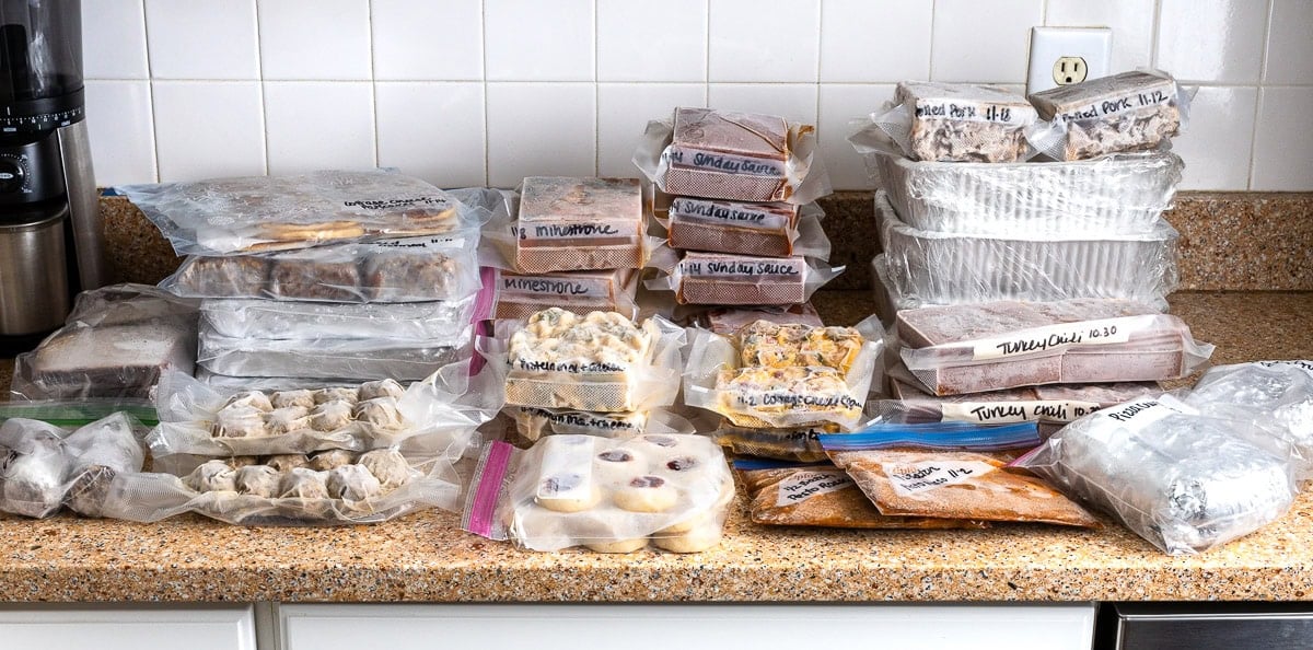 Separately packaged meals in bags and trays on a kitchen countertop.
