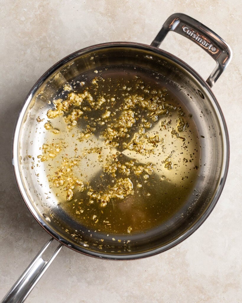 Garlic and oregano in a pan sautéing in oil.