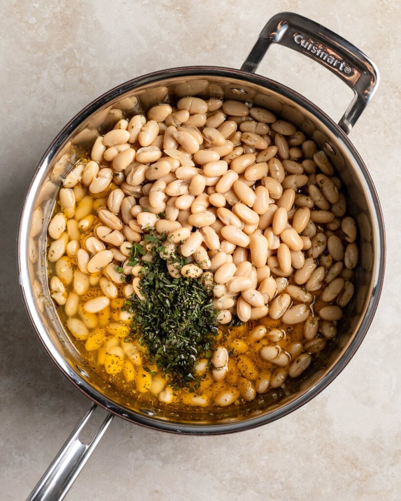 Beans, herbs, broth, and sun-dried tomatoes added to the pan.