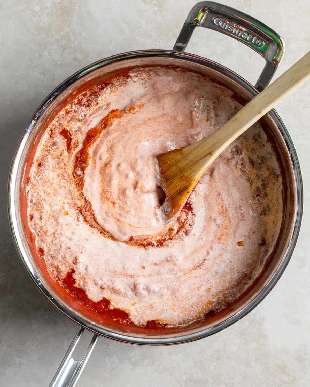 The tempered yogurt and half-and-half being stirred into the pan of sauce.