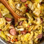 A wooden serving spoon in a skillet of fried cabbage ready to serve.
