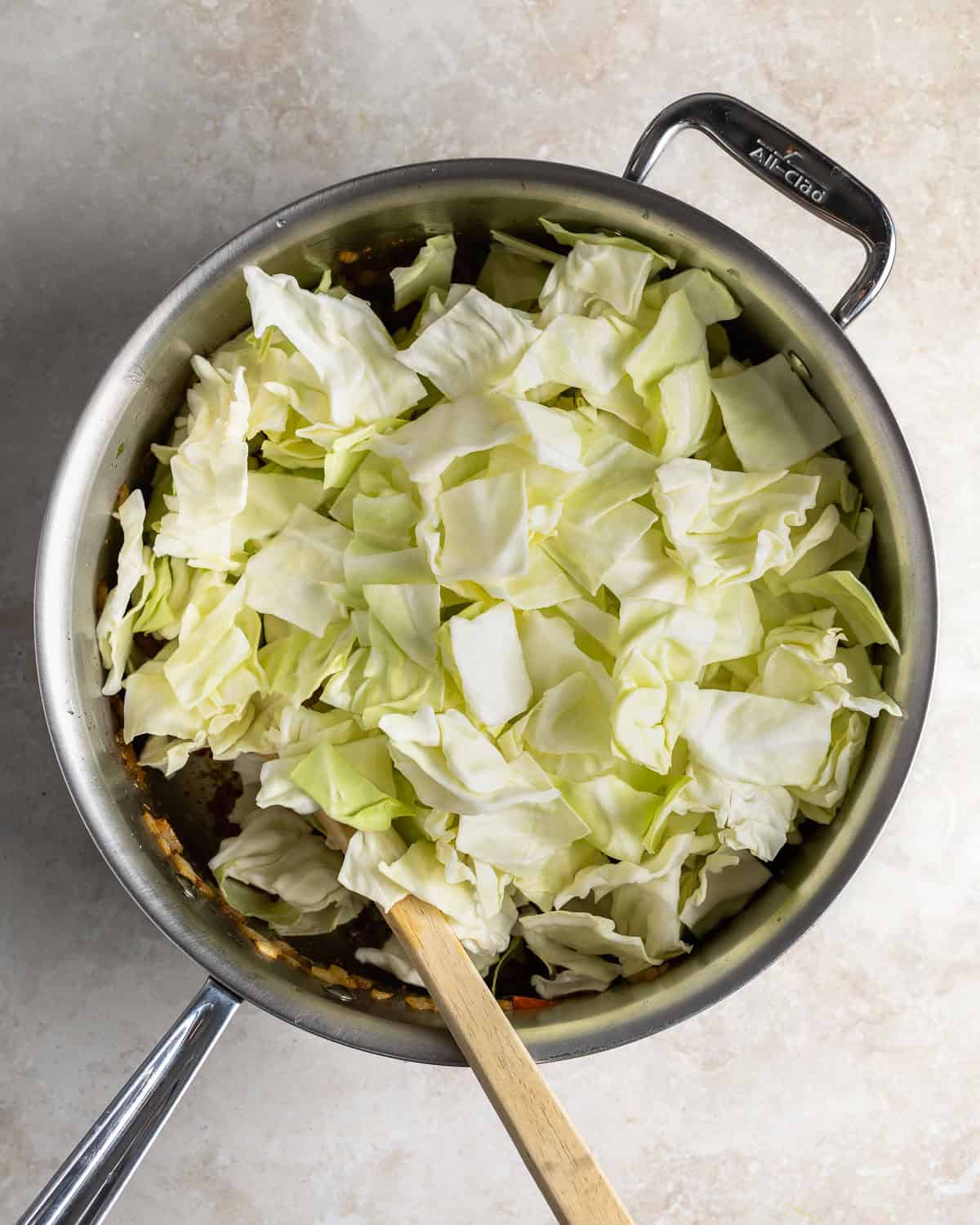 Sliced cabbage leaves being added to the pan of vegetables.