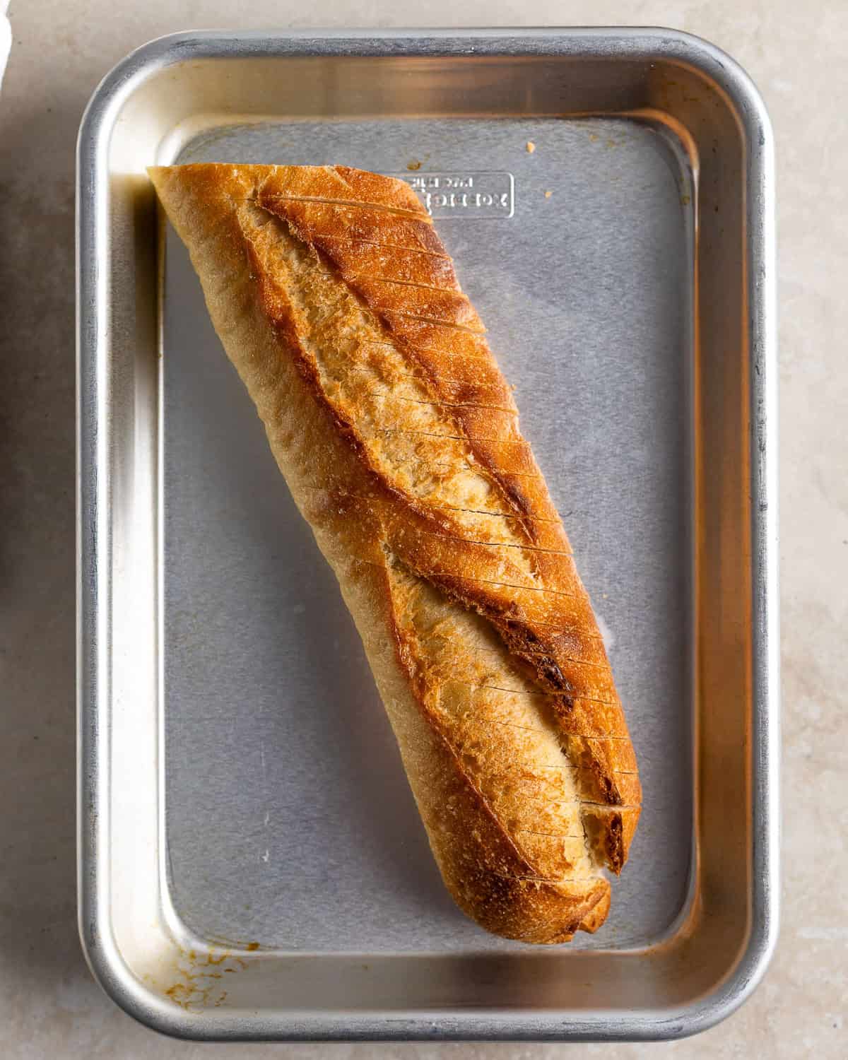 A sliced baguette on a small sheet pan.